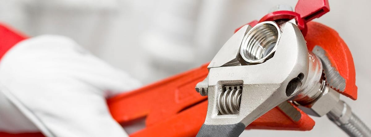 Close-up of a pipe wrench tightening a fitting